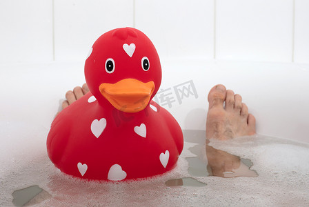 男人的脚在浴缸里，有大橡皮鸭