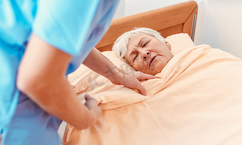 护理人员在养老金领取者家里拉着毯子盖住熟睡的老人