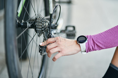 白天，女骑车人在户外山地自行车上检查自行车机构、链轮和链条的手部特写镜头