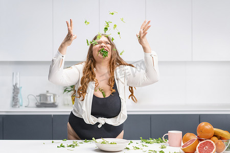指数摄影照片_快乐的胖女孩把菠菜叶撒得满桌子都是。