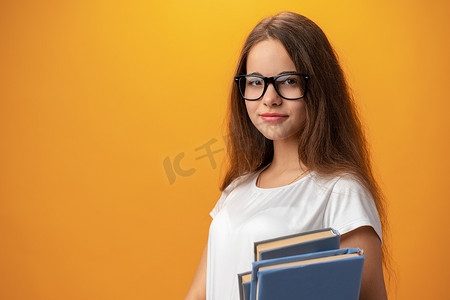戴眼镜的聪明少女拿着黄色背景的书
