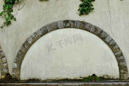 一扇带石拱门的围墙门，背景是旧米色灰泥墙、相框、文字位置