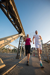 年轻夫妇慢跑过城市的桥