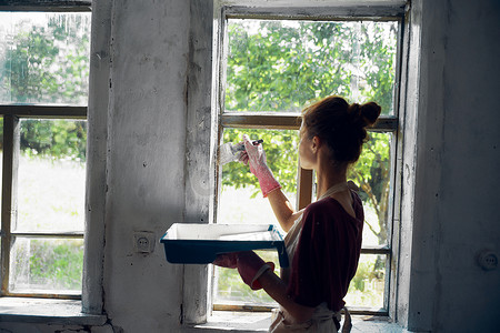 女人在房屋室内装修中油漆窗户