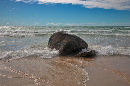 蓝水海滩的蓝天美丽沙滩上，海浪撞击背光巨石
