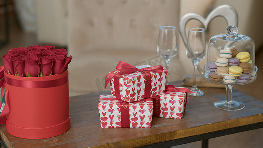 情人节礼盒，咖啡桌上放着红心包装纸，旁边是豪华红玫瑰花束
