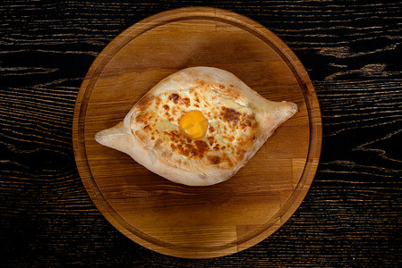 阿扎尔格鲁吉亚哈查普里，木制背景的黑盘上放着鸡蛋和奶酪民族传统美食。