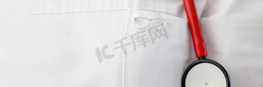 礼服图标摄影照片_挂在眼科医生礼服特写上的眼镜形状图标