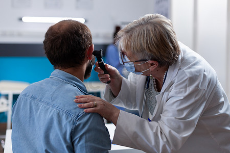 医生使用耳镜与患者进行耳部咨询的特写