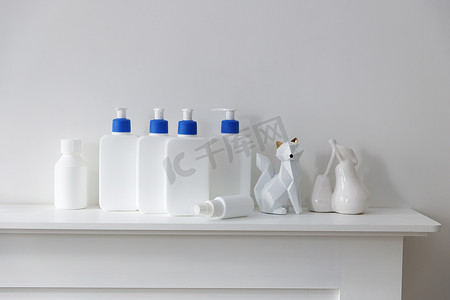 白色瓶子里有一个蓝色分配器，里面有洗发水、护发素、奶油和液体肥皂，小雕像站在浴室的架子上。