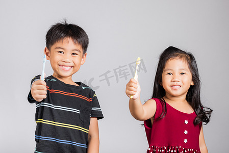 3-6 岁的小可爱男孩和​​女孩在工作室拍摄的隔离照片中刷牙和微笑
