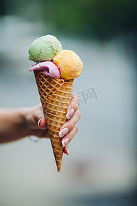 拿冰淇淋摄影照片_女人拿着美味的彩色冰淇淋。夏日氛围和甜食。