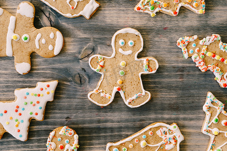 姜饼人饼干的特写，木质纹理，周围环绕着圣诞树和男人形状的装饰圣诞饼干。