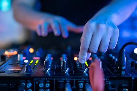 转盘摄影照片_夜总会中 DJ 手控制音乐桌的特写前视图。