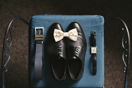 男皮带摄影照片_椅子上有男鞋、手表、皮带、领带和戒指。