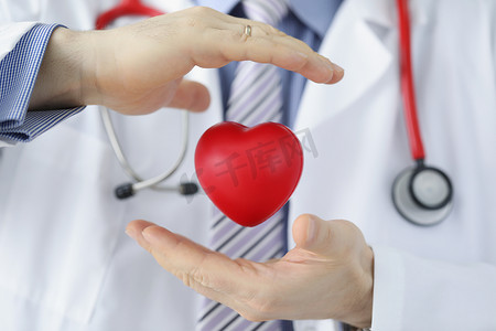 医务人员保护塑料红心，医生用手遮盖心脏模型