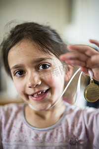 奖牌冠军摄影照片_6岁女孩展示脖子上挂着的奖牌