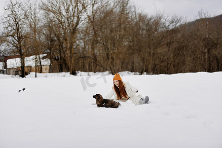 宠物狗玩耍摄影照片_快乐的女人在雪地里和狗玩耍有趣的友谊寒假