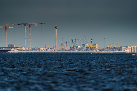 海平线摄影照片_海港、建筑起重机和货港起重机在日落光下的海平线上