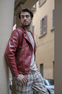 皮夹克摄影照片_雷焦艾米利亚市中心穿着红色皮夹克和背包的帅哥