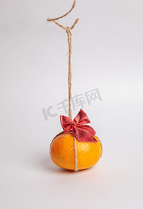 蝴蝶结绳子摄影照片_喜庆的橘子，绳子上挂着红色的蝴蝶结。