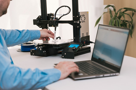 原型摄影照片_年轻工程师在实验室调整 3D 打印机的组件