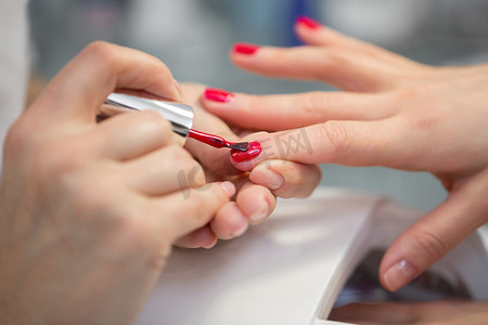 女美甲师在美容院给女顾客做指甲。