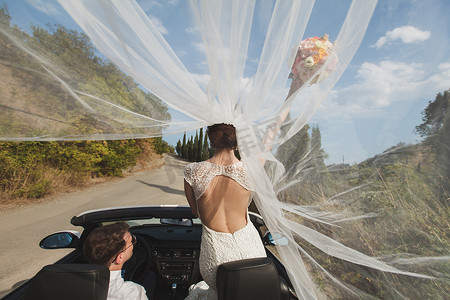 美丽时尚的年轻成功夫妇在热带国家或岛屿的婚礼散步中享受乘坐汽车的乐趣。