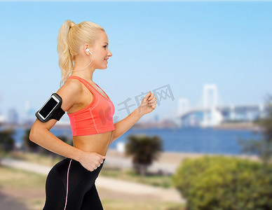 用智能手机和耳机跑步的运动型女性