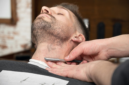理发师用锋利的剃刀剃胡子的男性