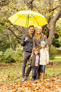伞下的男孩摄影照片_微笑的年轻家庭在伞下
