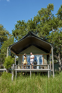 一对男女在豪华野生动物园的野生动物园帐篷前，南非，丛林中的豪华野生动物园小屋