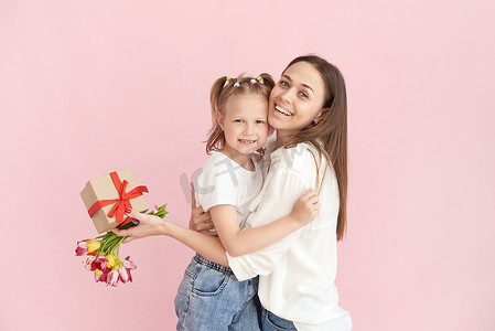 送花的兔子摄影照片_在工作室里，一个小女儿在粉色背景下给妈妈送花和母亲节礼物。
