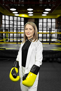拳击场背景上戴着黄色拳击手套的女商人的肖像。