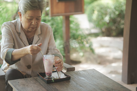 老老年老年妇女在露台上吃冰淇淋。