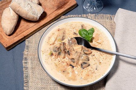 法式大餐摄影照片_自制奶油鸡肉和蘑菇汤或法式鸡肉炖菜，放在木桌上的汤碗里。