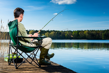 湖边摄影照片_坐在码头上的湖边钓鱼的男子