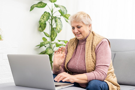 严肃的成熟老年女性在家或在办公室使用笔记本电脑观看培训网络研讨会。 