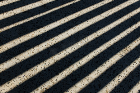 阳光透过木栅栏照射进来，在地面上留下几何条纹的影子。