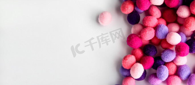 一堆白色的粉摄影照片_特写彩色 pom poms 背景，一堆柔和的彩色蓬松小球，用于工艺品和时尚配饰装饰，有选择的焦点