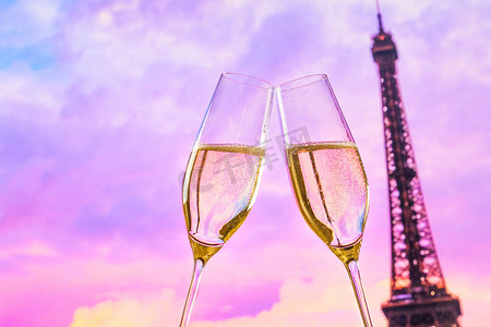 日落模糊塔埃菲尔铁塔背景上一对带有金色气泡的香槟笛