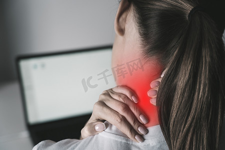 颈部疼痛摄影照片_使用笔记本电脑工作后颈部疼痛的女性
