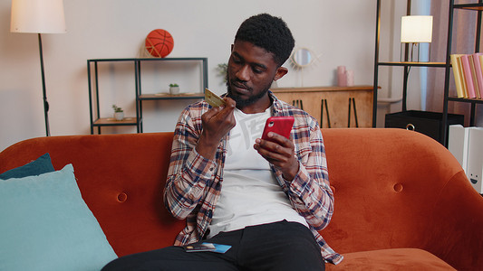 黑色高端ppt摄影照片_男子坐在家里使用信用卡和智能手机，同时在网上购物转账