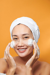 年轻的亚洲女性在脸上涂抹保湿霜。