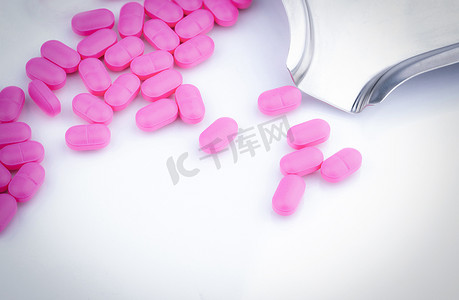 抗菌药物摄影照片_不锈钢药物托盘附近白色背景上的一堆粉色药片。