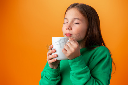 一杯热咖啡摄影照片_橙色背景中昏昏欲睡的少女拿着一杯热咖啡