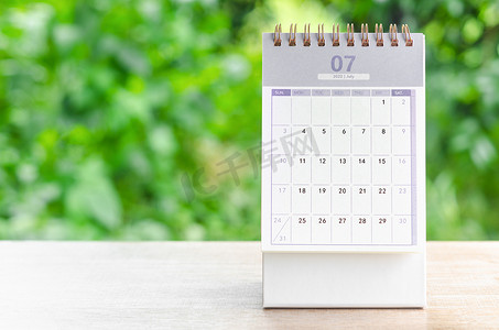 2022 年 7 月日历桌，供组织者在自然背景的木桌上进行计划和提醒。