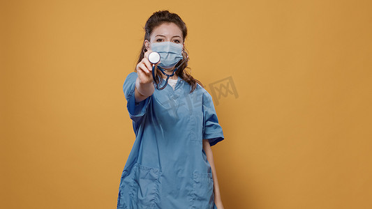 戴着新冠病毒防护面具的女医生戴上听诊器并在镜头前展示