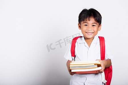 亚洲可爱的幼儿微笑着快乐地穿着学生泰式制服红裤立书学习准备上学