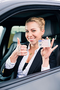 驾校x架摄影照片_显示驾驶执照和竖起大拇指的女人